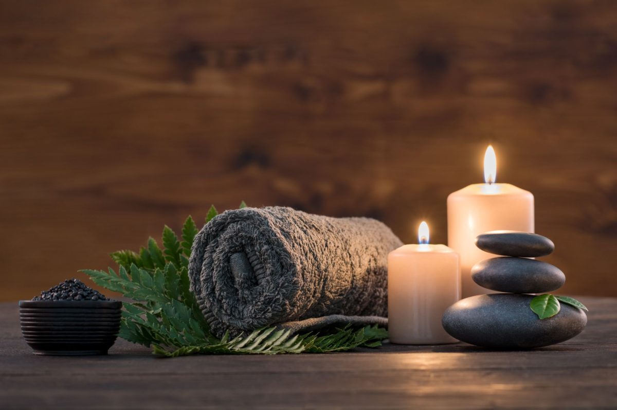 spa towel, rocks and candles sitting on a fern